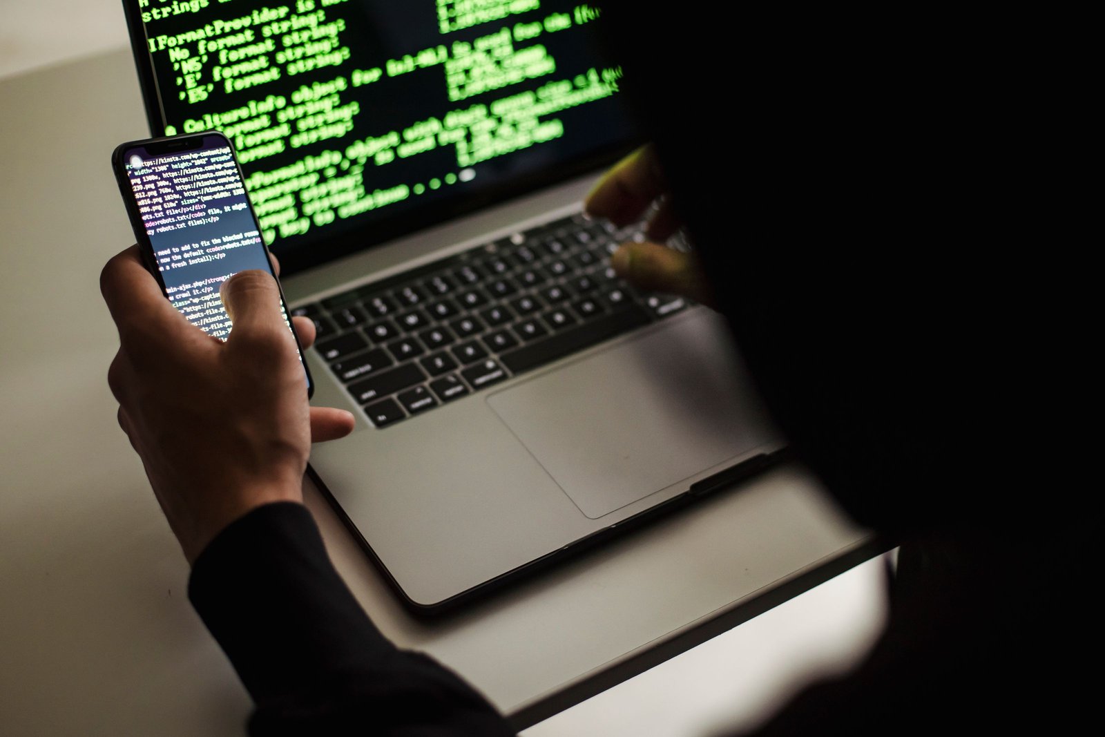 Developer researching an app on a laptop and smartphone